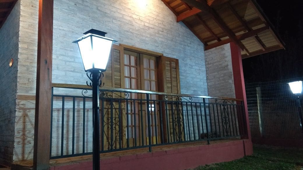Un edificio con balcón, una lámpara y una ventana con contraventanas.
