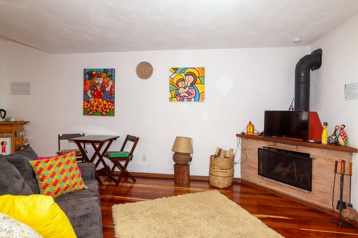 Uma sala de estar com sofá, poltronas, lareira e duas pinturas nas paredes.