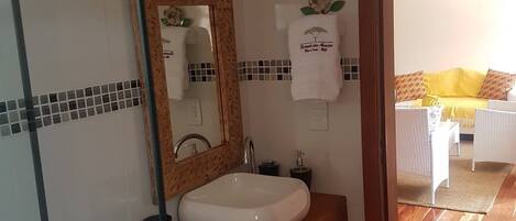 Un baño con un lavamanos blanco, un tocador de madera, un espejo con un marco decorativo y una toalla con un logotipo.