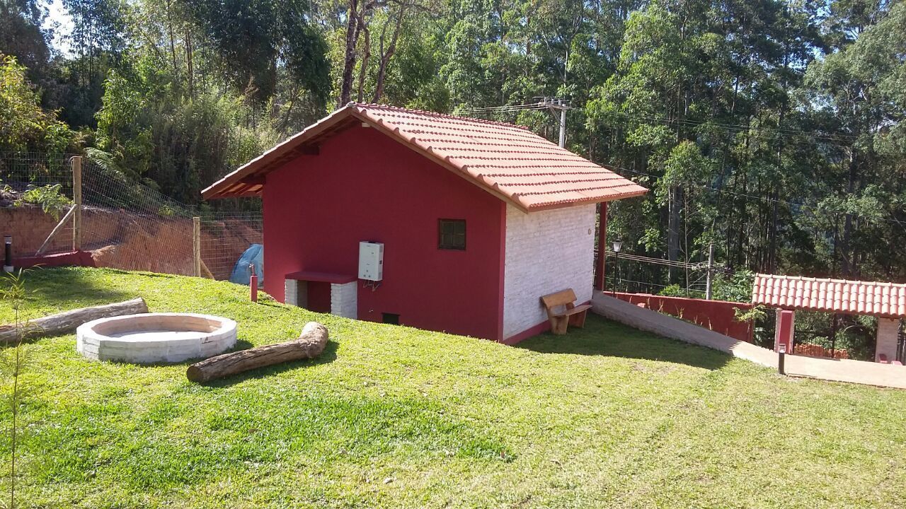 A red and white building with a sloped roof, surrounded by a fenced area and a grassy field.