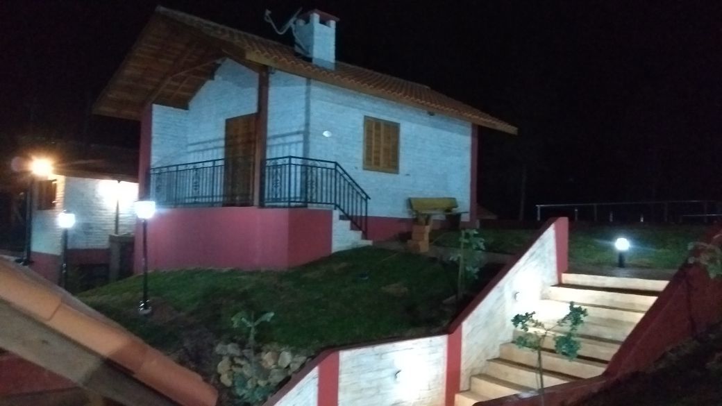 A two-story house with a balcony, stairs, and a small garden area.