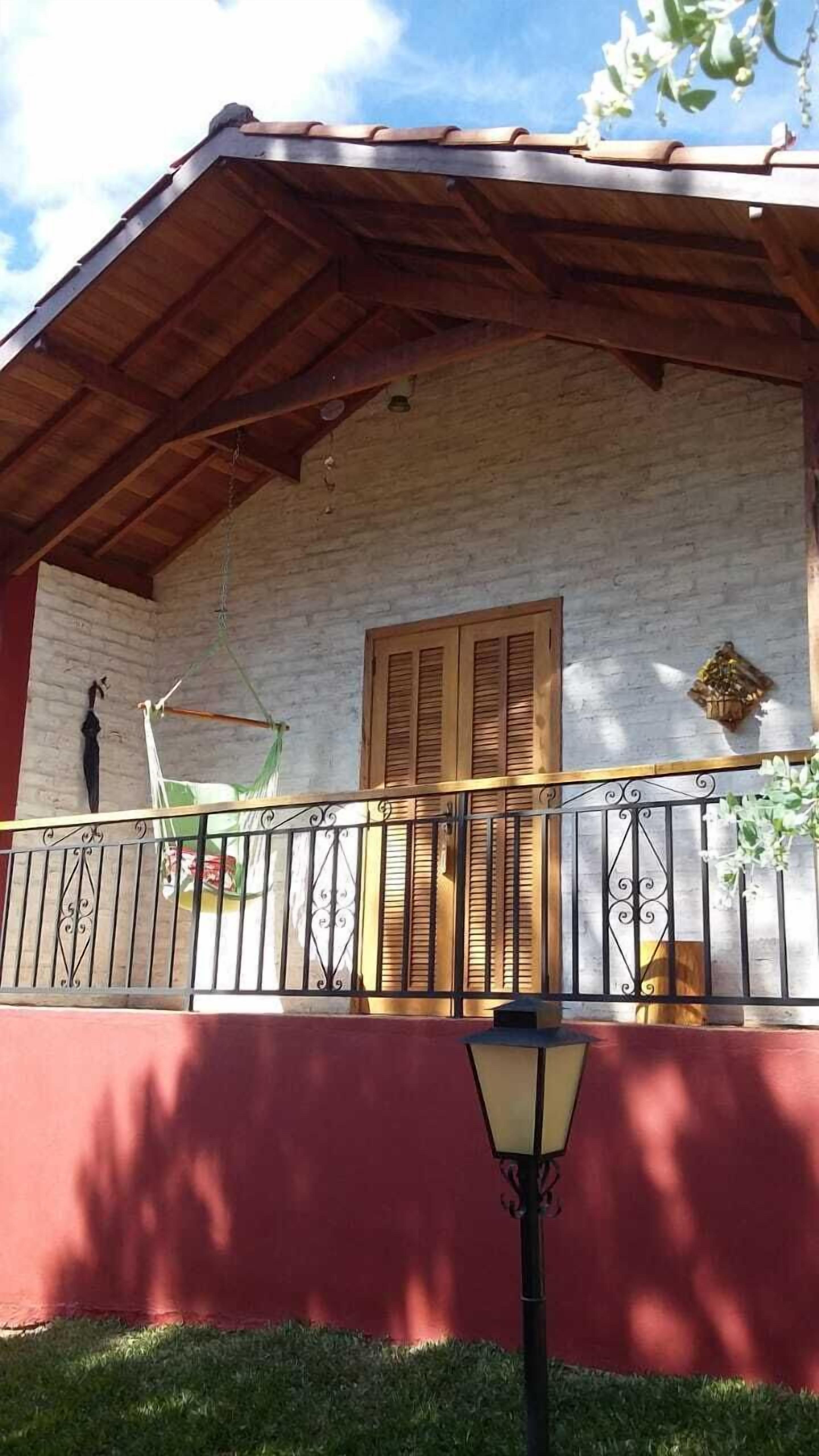 A covered porch with a wooden railing, a hanging hammock, and a lantern.