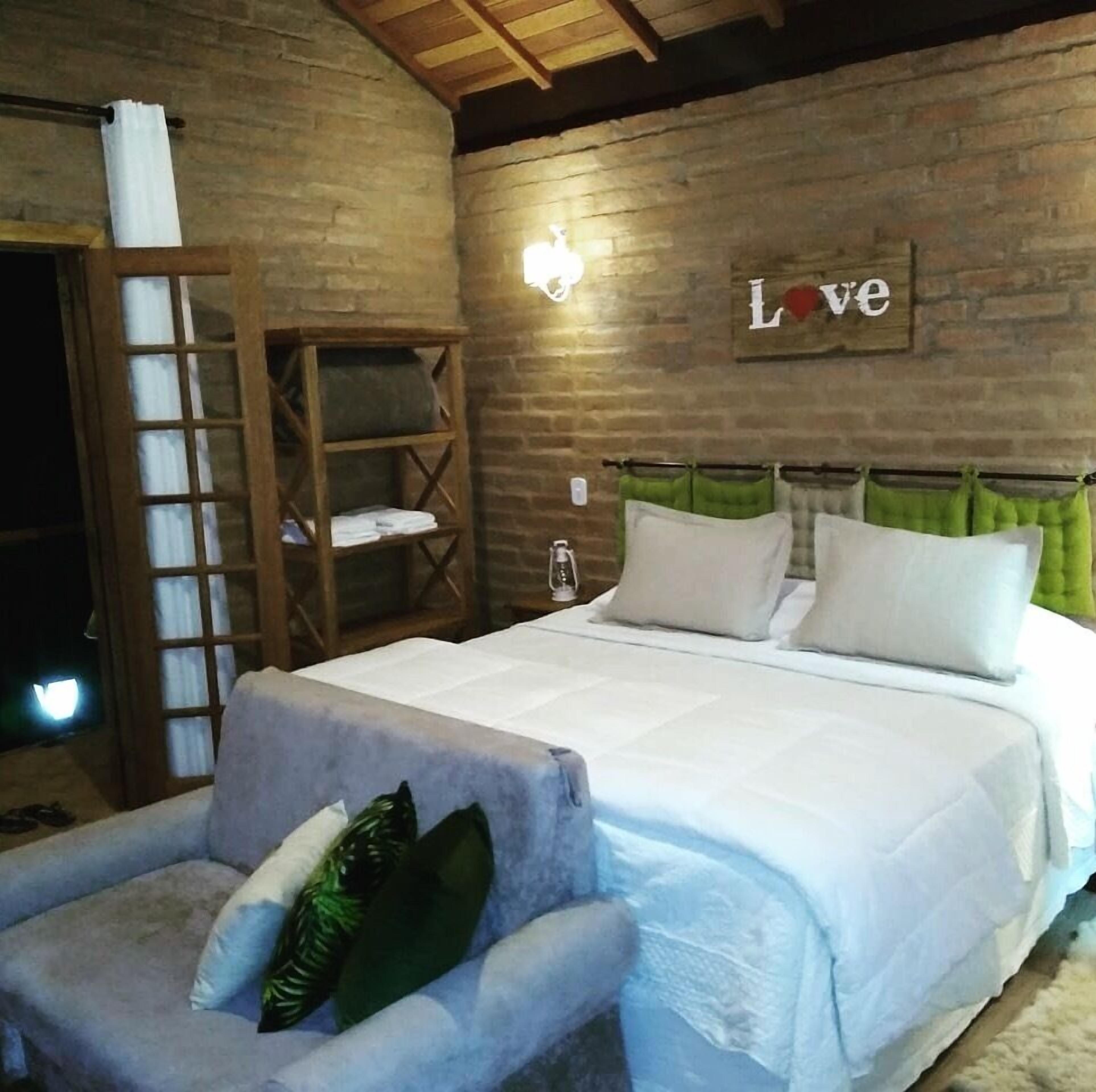 A bedroom with a bed, a wooden shelf, a chair, and a 'Love' sign on the wall.