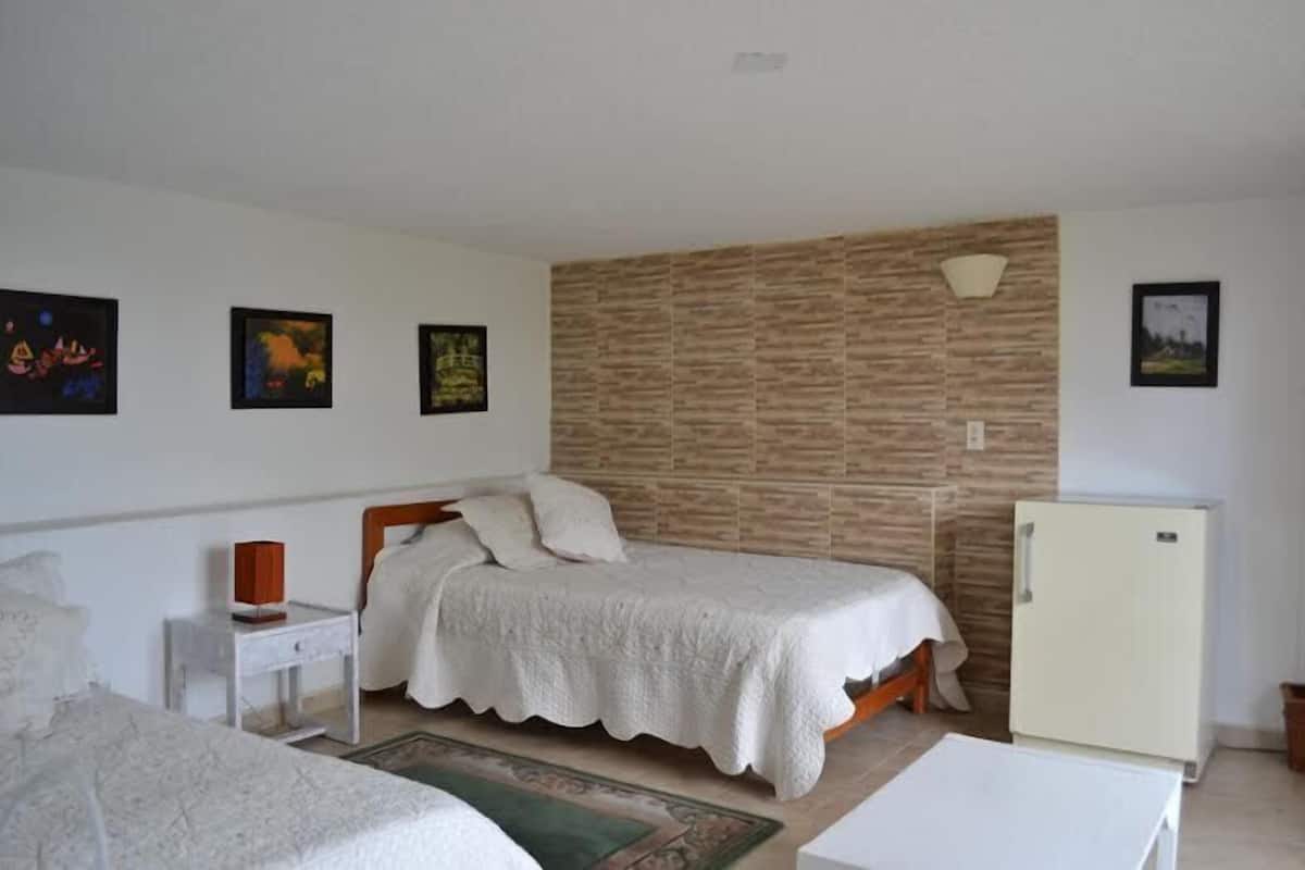 Ein Schlafzimmer mit einem Bett, einem Nachttisch, einer Kommode, einem Kühlschrank und einer Wand mit Struktur.