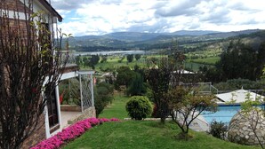 Propiedad residencial con vista a un lago, piscina y jardín con plantas en flor.