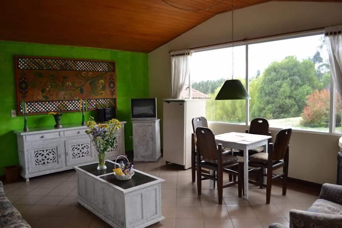 Ein Essbereich mit Tisch, Stühlen, einem Fernseher und einem Kühlschrank.