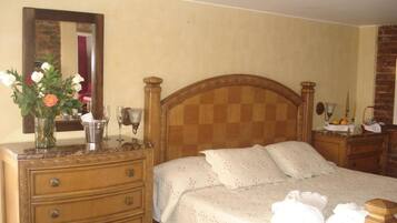 Un dormitorio con una cama de madera, un aparador con cajones, un espejo y un florero con flores.