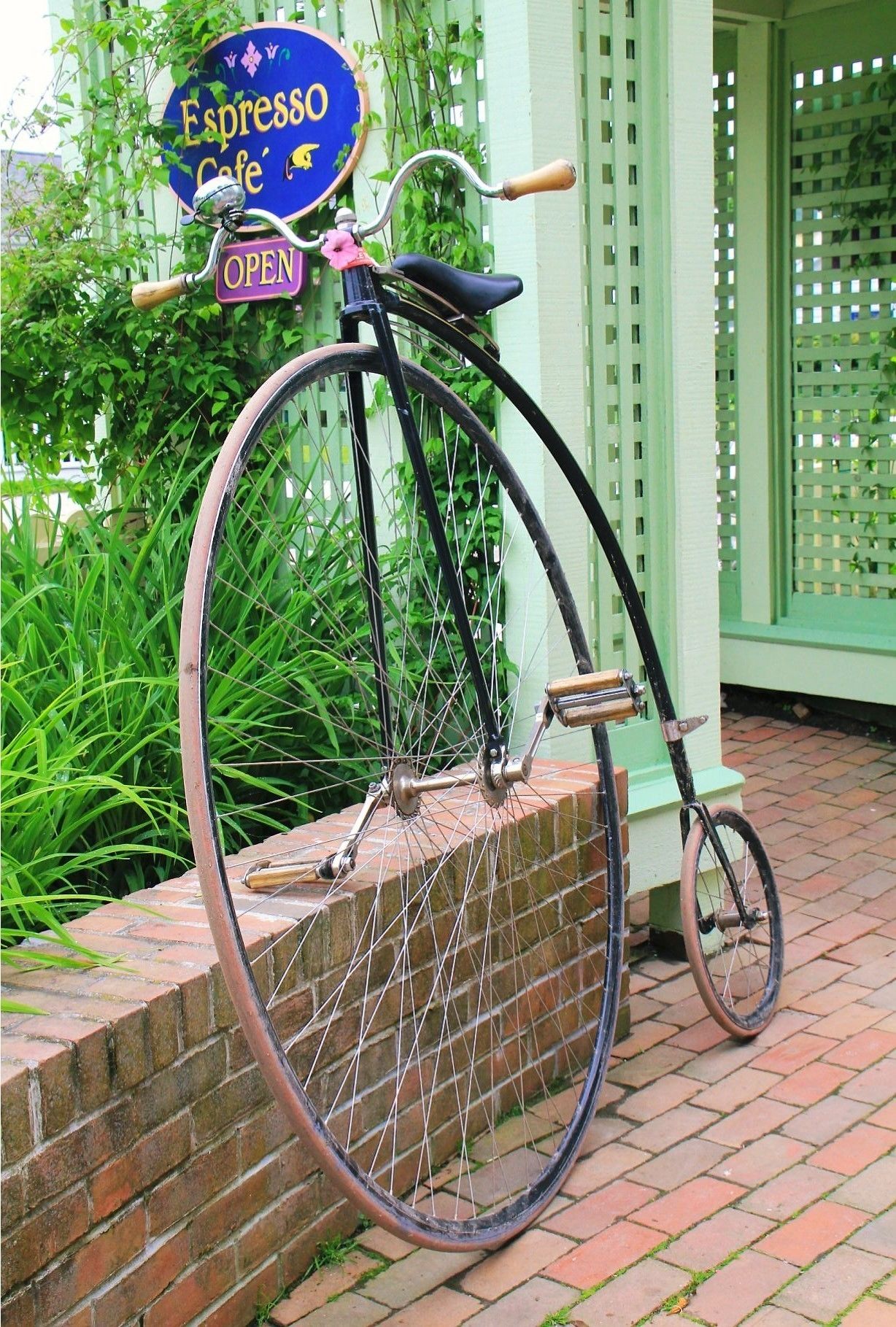Uma bicicleta antiga estacionada em frente a um edifício com uma placa que diz 'Espresso Cafe' e 'ABERTO'.