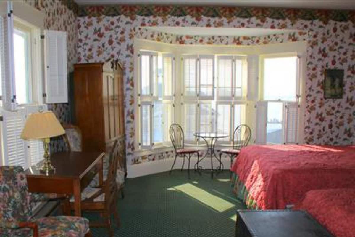 A room with a bed, a desk, a chair, and a window with multiple panes.