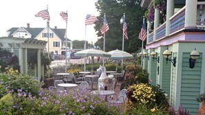 Une terrasse de jardin avec des sièges d’extérieur, des drapeaux américains et un kiosque.