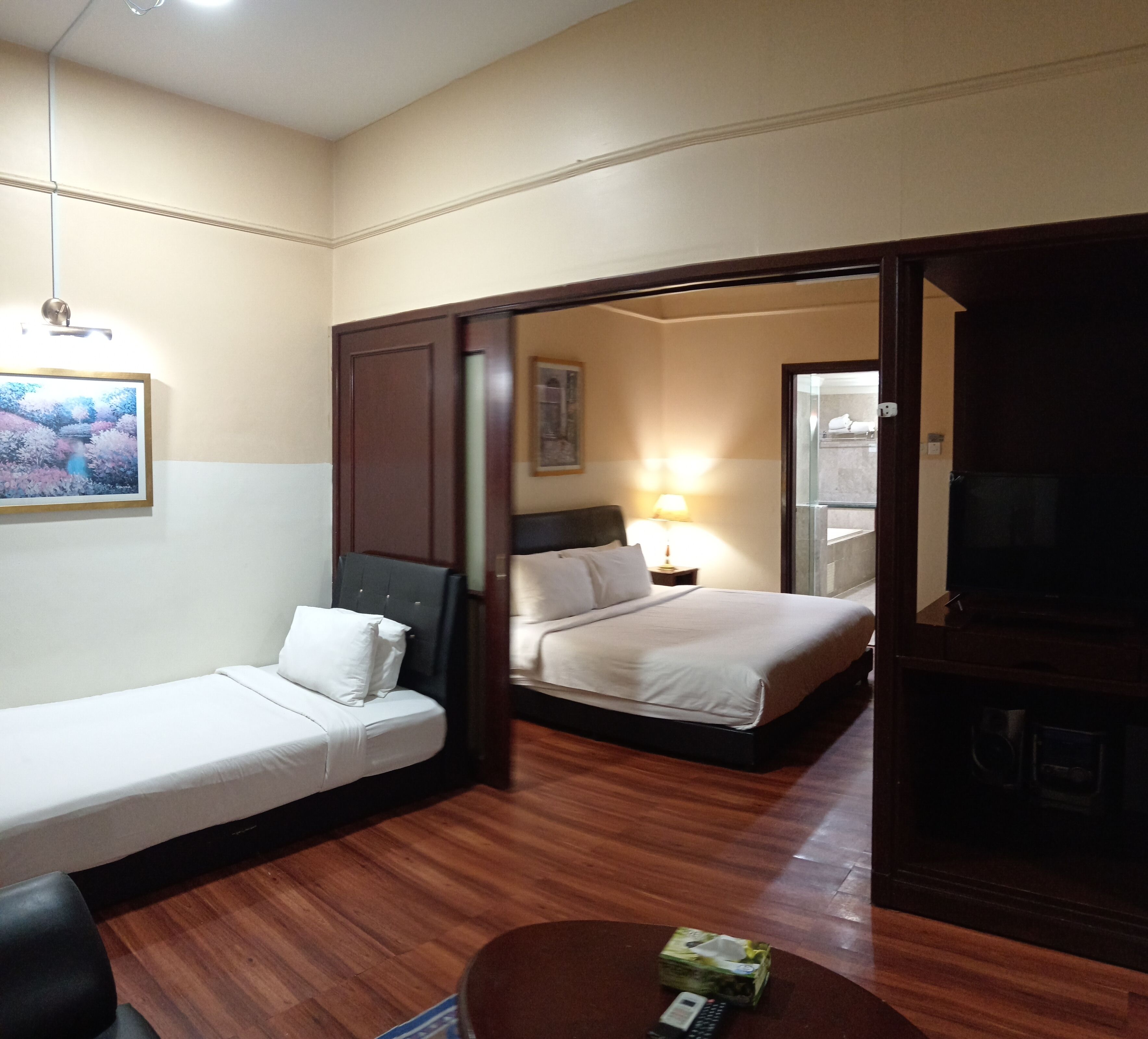 A hotel room with a bed, a sofa, a small table, and a TV.
