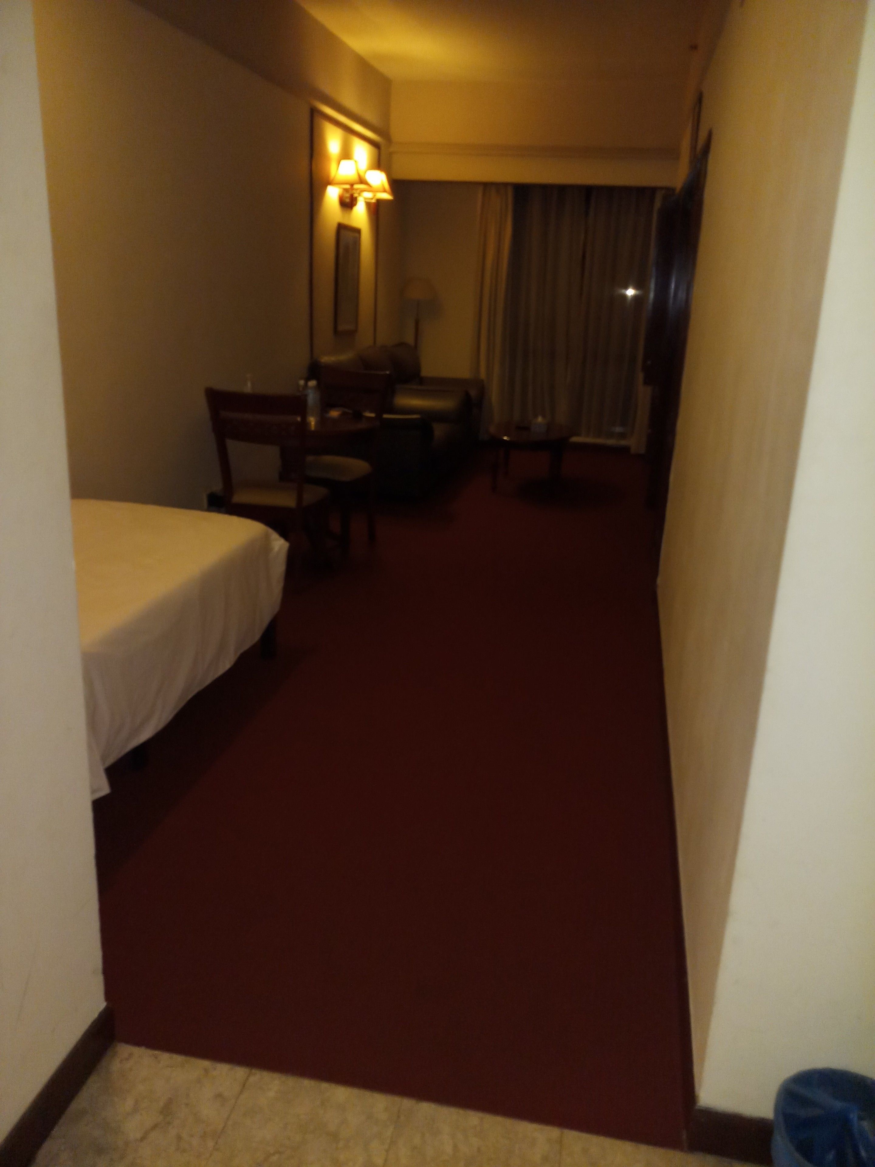 Une chambre d’hôtel avec un lit simple, un bureau, une chaise et une petite table.