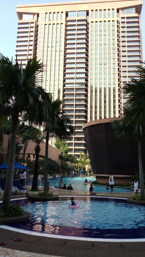 A hotel with a large swimming pool surrounded by palm trees and lounge chairs. - Falcon Apartment At Times Square (Kuala Lumpur)
