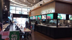 Un restaurante con una decoración moderna, que presenta una barra con pantallas digitales del menú y un letrero que dice "BANANABRO".