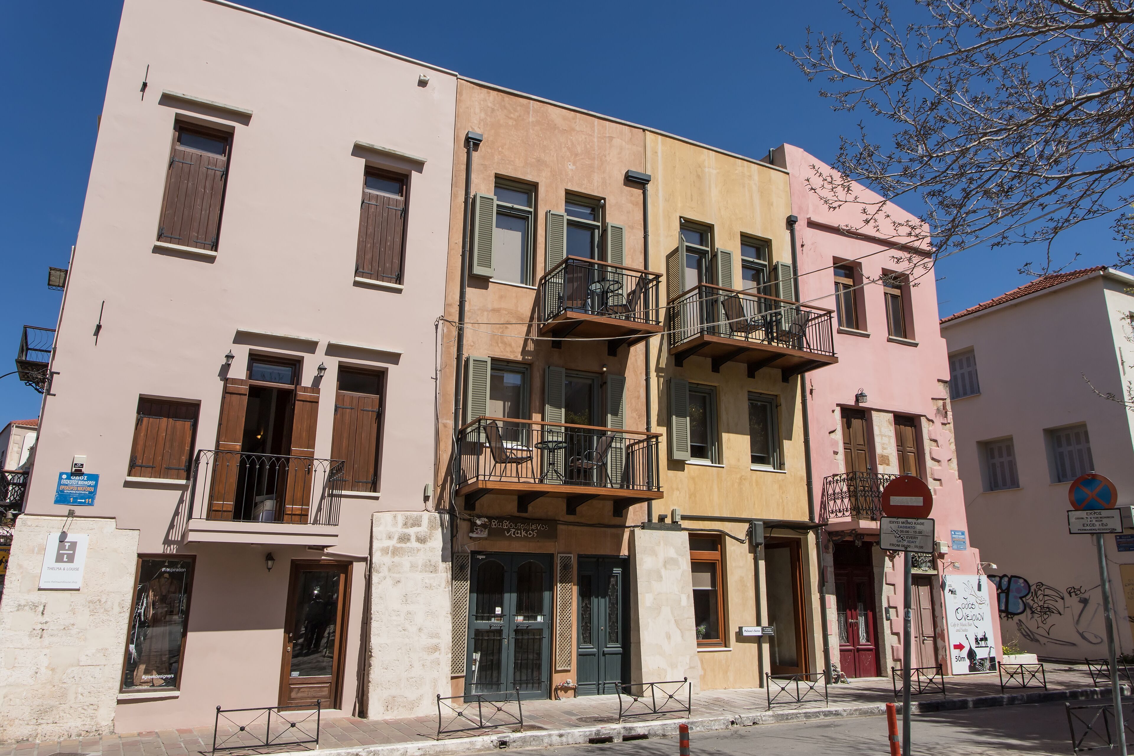 Un edificio de varios pisos con balcones, un letrero de restaurante y una señal de no estacionamiento.