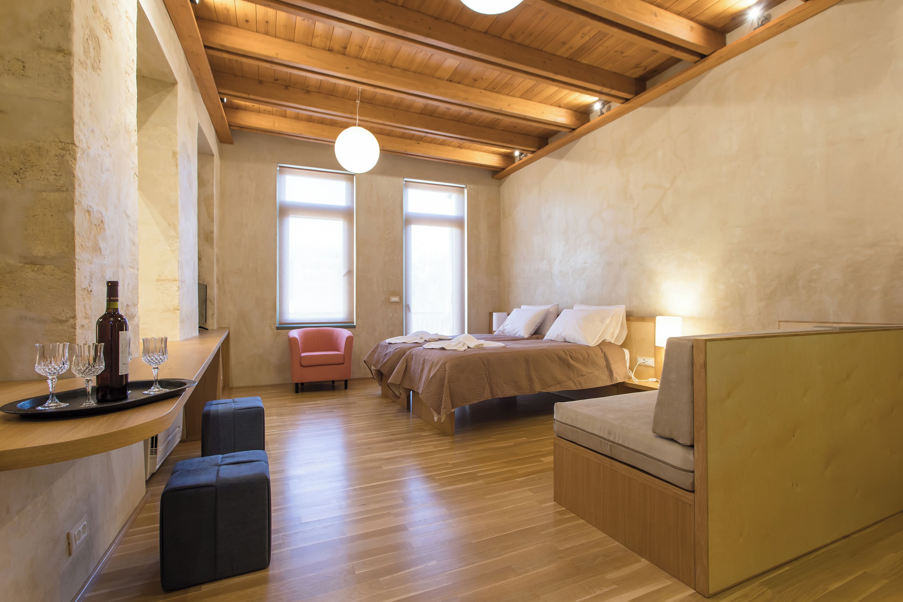 Une chambre à coucher moderne avec un plafond en bois, un lit doté d’une tête de lit, une table de chevet et une chaise.