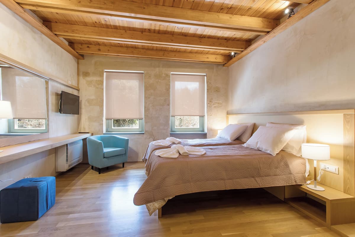 A bedroom with a bed, bedside tables, a chair, and a TV.