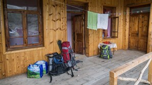Een houten blokhut met een veranda, houten wanden en een houten bankje. Er liggen tassen en een rugzak op de veranda.