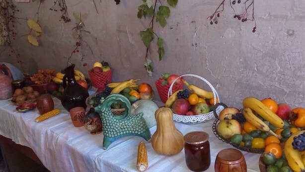 Een tafel met verschillende soorten fruit, groenten en decoratieve objecten.