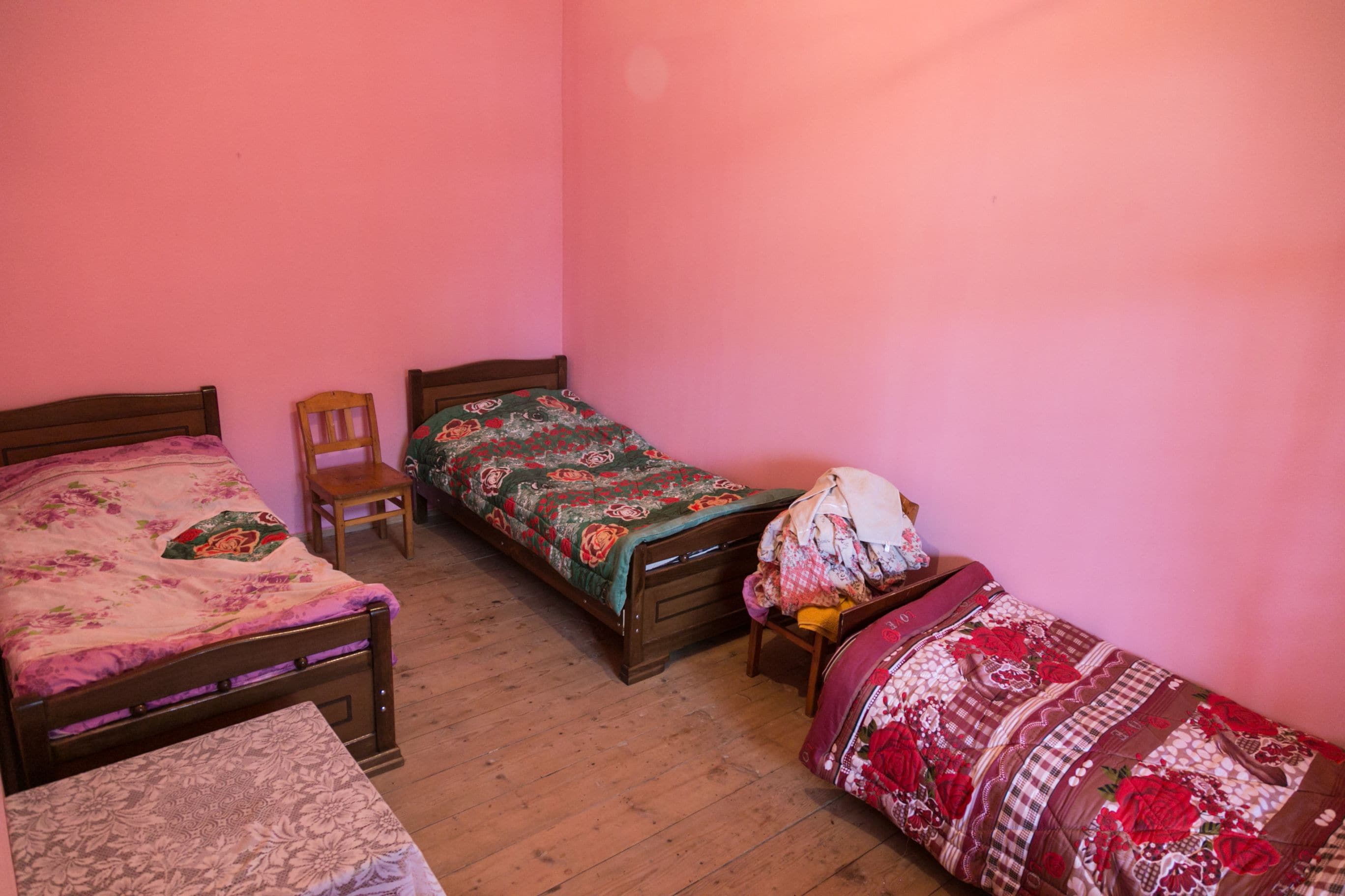Un dormitorio con dos camas de madera, una silla y una mesita.