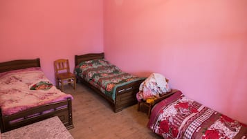 Un dormitorio con dos camas de madera, una silla y una mesita.