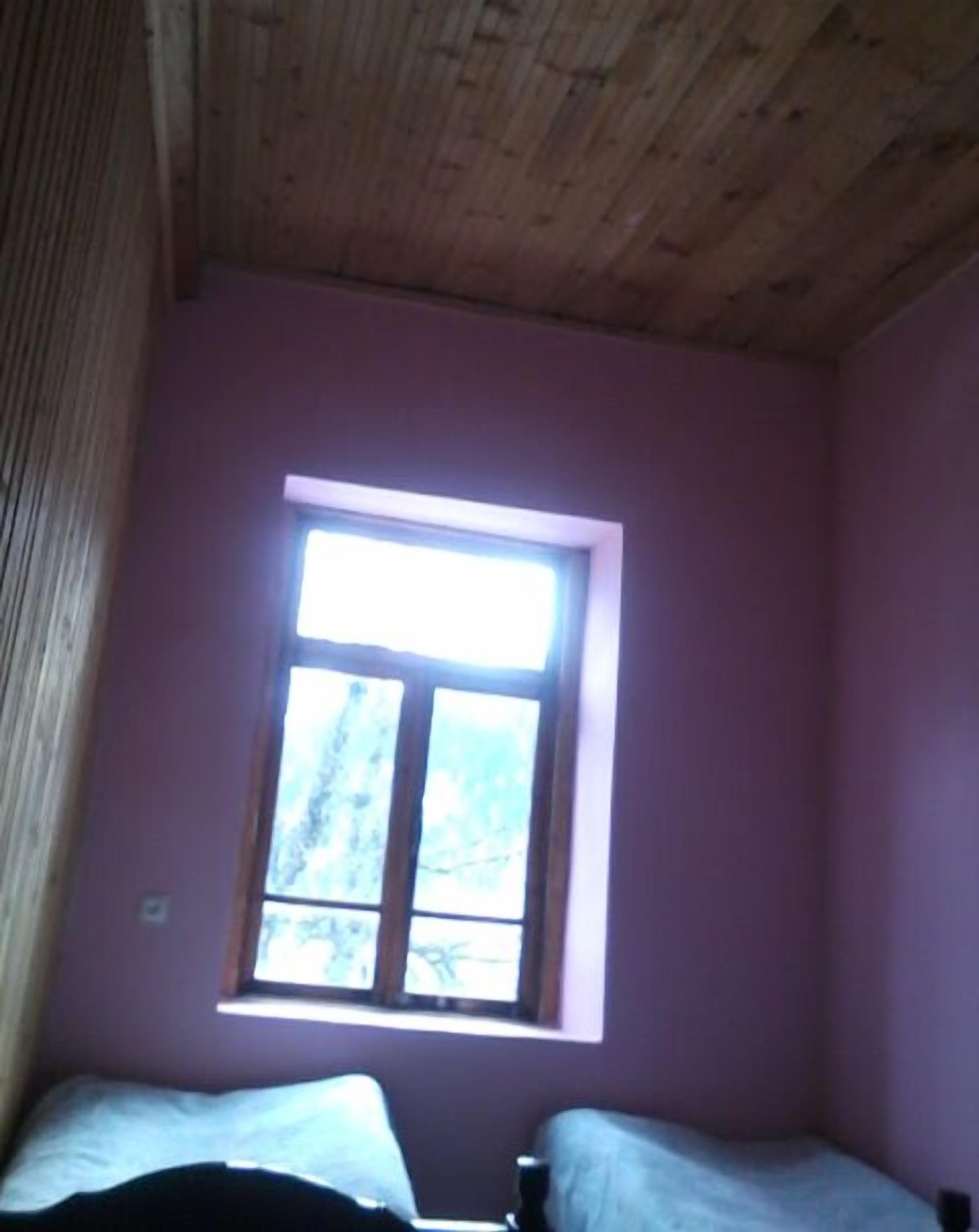 Una habitación con un ventanal, techo de madera y paredes moradas.