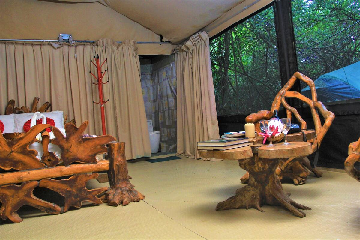 Ein Zimmer mit großem Fenster, Holzmöbeln und einem Tisch mit Büchern und einer Kerze.