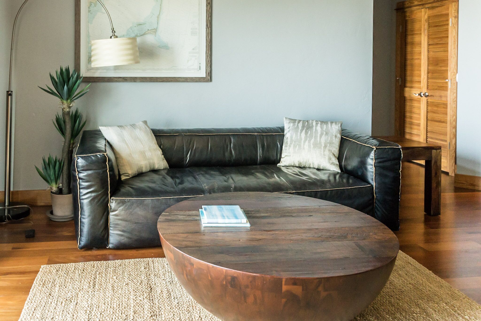 Ein modernes Wohnzimmer mit einer Ledersofa, einem Holztisch und einer Zimmerpflanze.