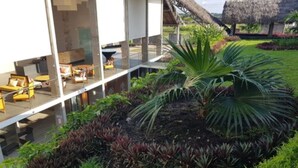 Un edificio moderno con fachada de vidrio, zona de estar al aire libre y un jardín cuidado con diversas plantas.