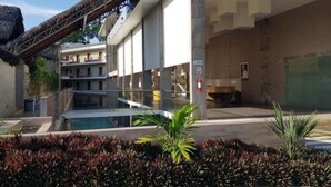 Un hotel moderno con piscina, asientos al aire libre y un área techada con techo de paja.