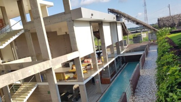 Un edificio moderno con piscina, mobiliario exterior y una escalera.
