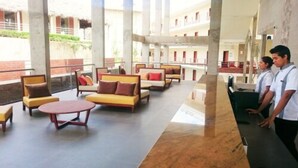 Un vestíbulo amplio con varias zonas de estar, una recepción y vistas del exterior del edificio.