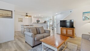 Ein modernes Wohnzimmer mit einem grauen Sofa, einem Holztisch und einem Flachbildfernseher auf einer Holzkommode.