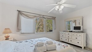 Ein Schlafzimmer mit Bett, Kommode, Fernseher und Deckenventilator.