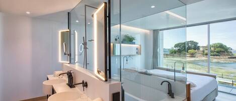 A modern bathroom with three sinks, a large mirror, and a view of a river.