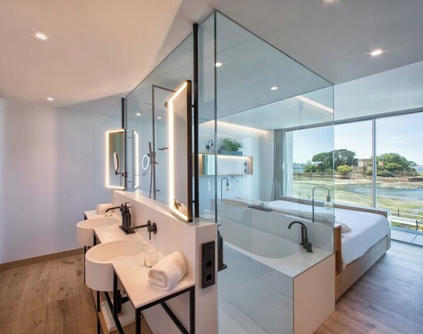 A modern bathroom with three sinks, a large mirror, and a view of a river.