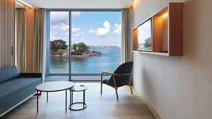 A modern room with a large window, a sofa, a chair, and a small table. - Noa Boutique Hotel (Oleiros)