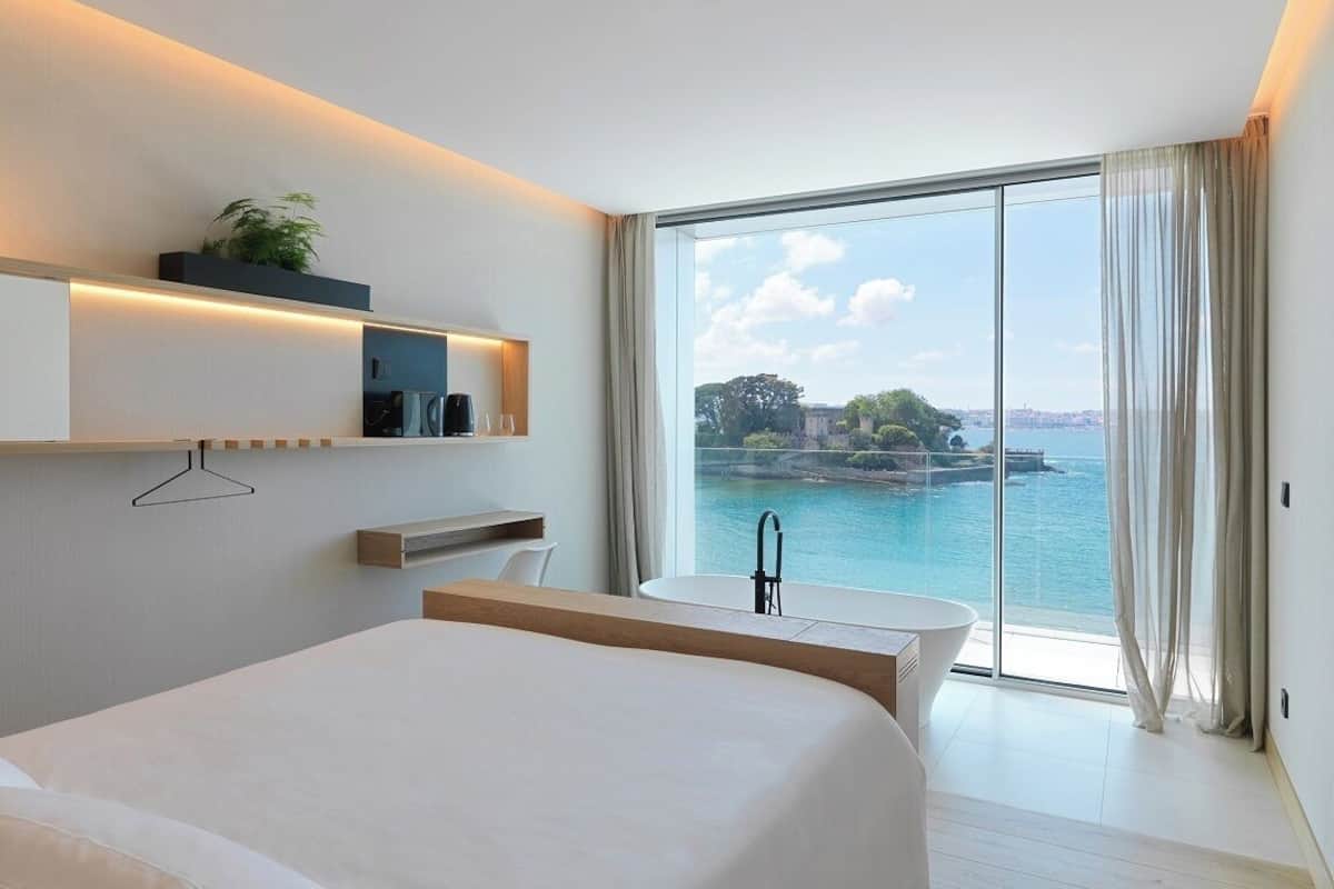 Une chambre d’hôtel moderne avec un grand lit, un bureau et une vue sur la mer.