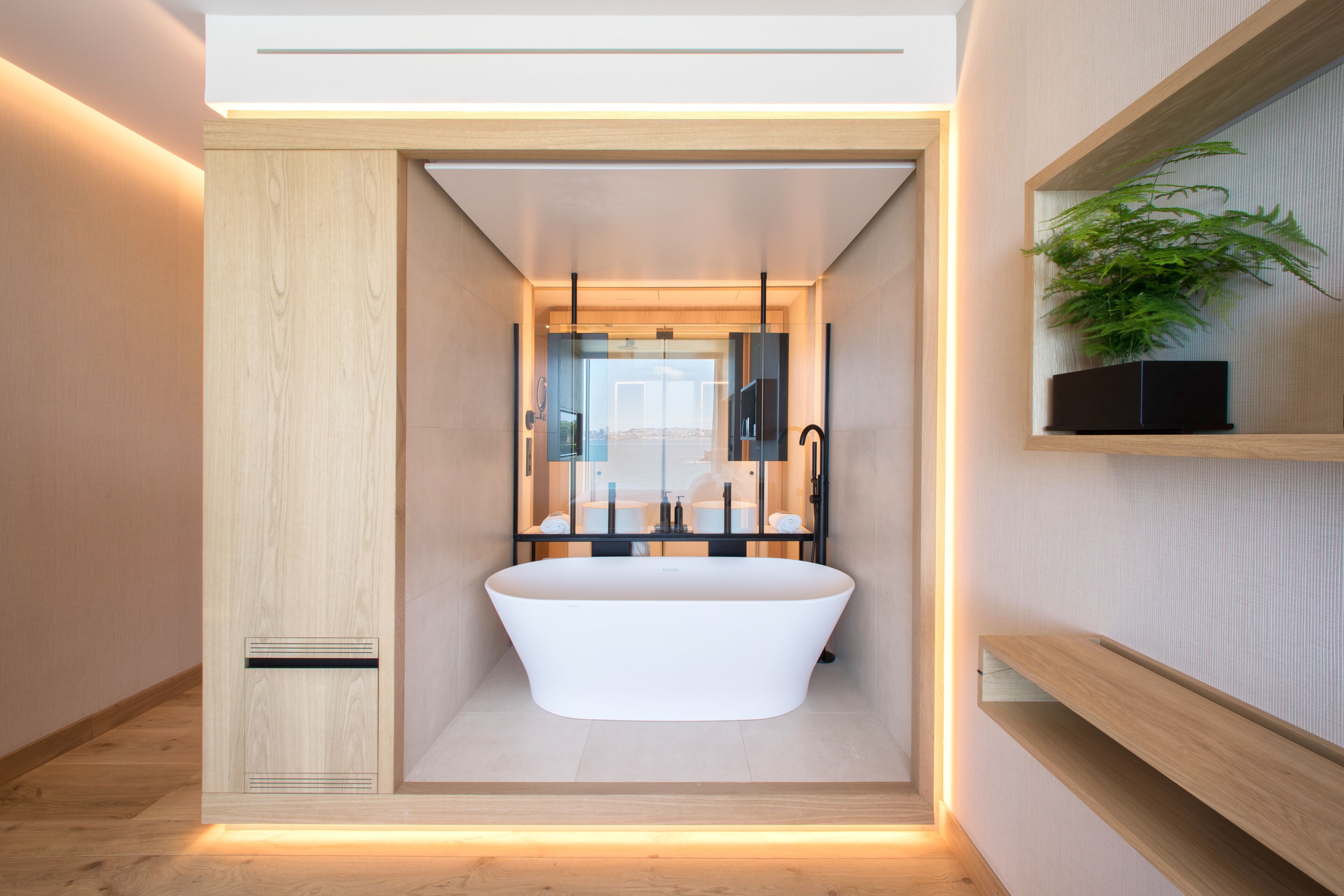 A modern bathroom with a freestanding bathtub, a glass enclosure, and a wooden vanity with a plant.