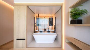 A modern bathroom with a freestanding bathtub, a glass enclosure, and a wooden vanity with a plant.