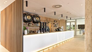 A modern bar area with a white counter, wooden paneling, and a ceiling with a unique design. - Noa Boutique Hotel (Oleiros)