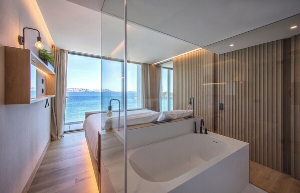 A modern bedroom with a large window, a bathtub, and a wooden wall. - Noa Boutique Hotel (Oleiros)
