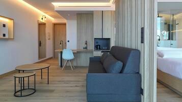 Una habitación de hotel moderna con sofá, una mesita, televisor y cama.