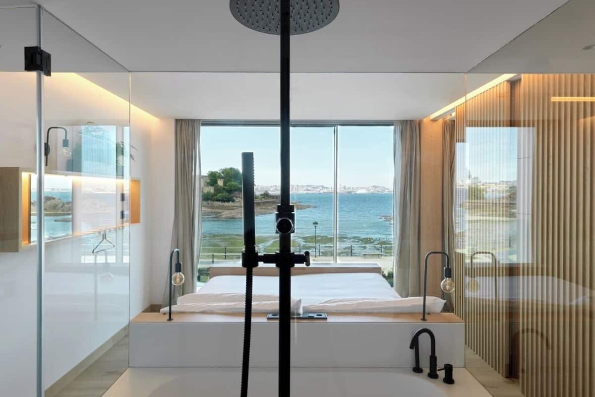 Une chambre d’hôtel moderne avec un grand lit, une douche et une vue sur la mer.