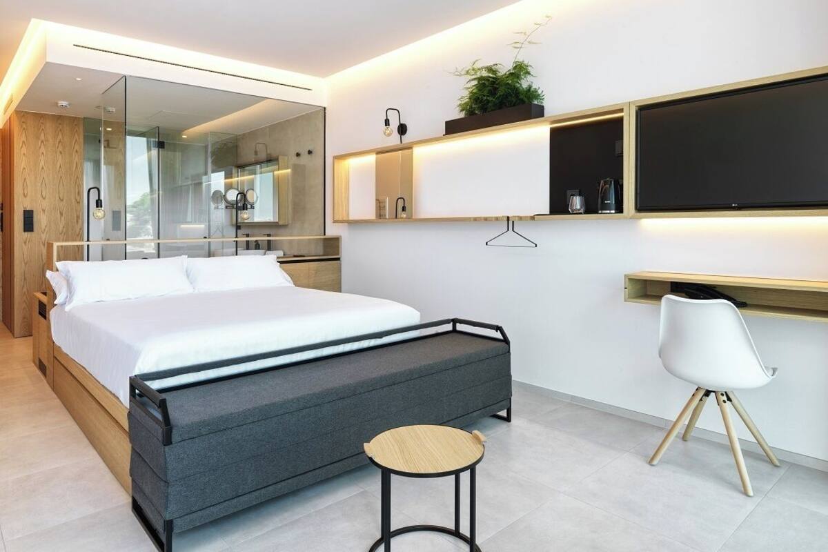 Une chambre à coucher moderne avec un lit, des tables de chevet, un bureau et une chaise.