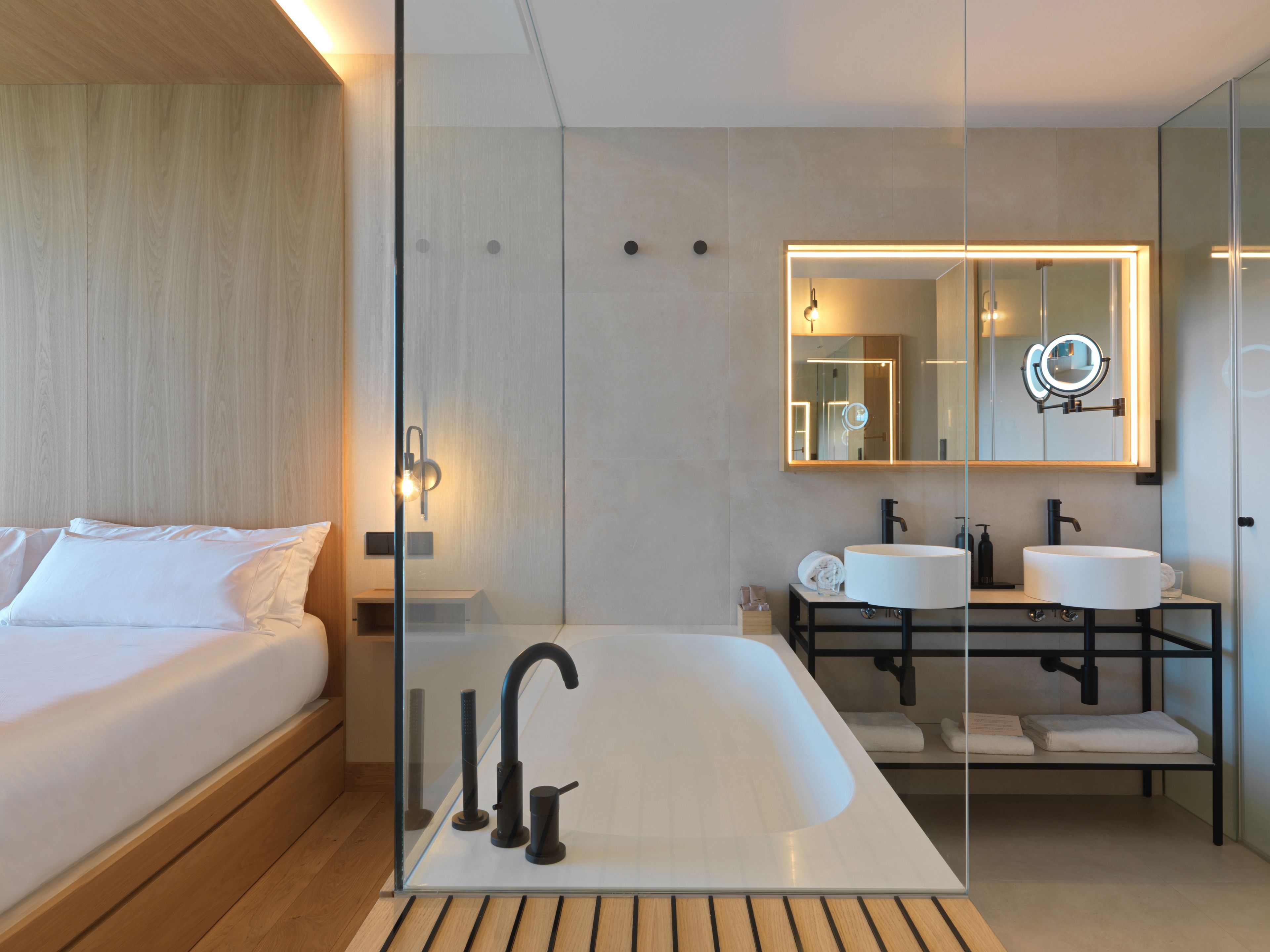 Un bagno moderno con una vasca da bagno ampia, due lavandini e uno specchio con illuminazione integrata.