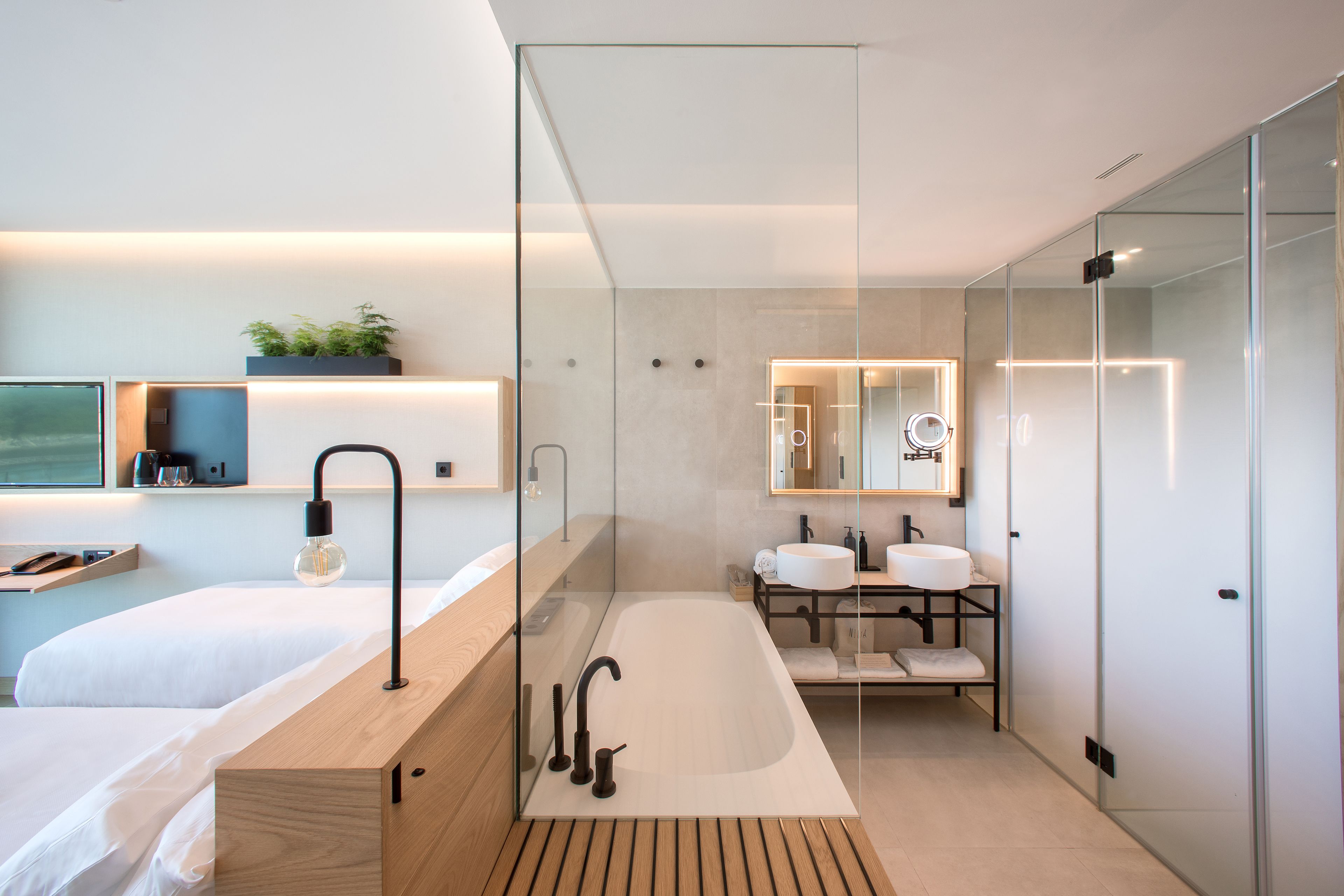 Un baño moderno con ducha de vidrio, tocador de madera y un espejo grande.