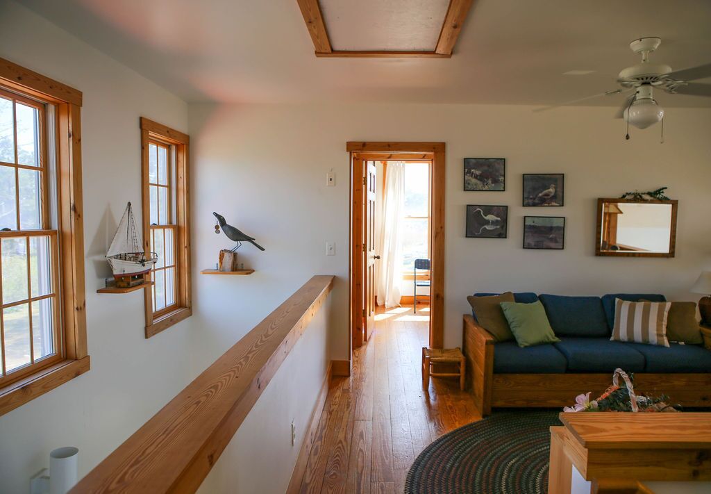 A spacious living area with a wooden floor, a green sofa, and a ceiling fan.