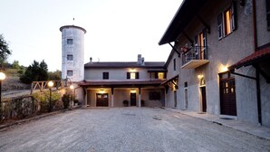 Um edifício de dois andares com um caminho de acesso de cascalho e uma torre.