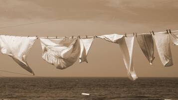 A clothesline with various garments hanging over a body of water.